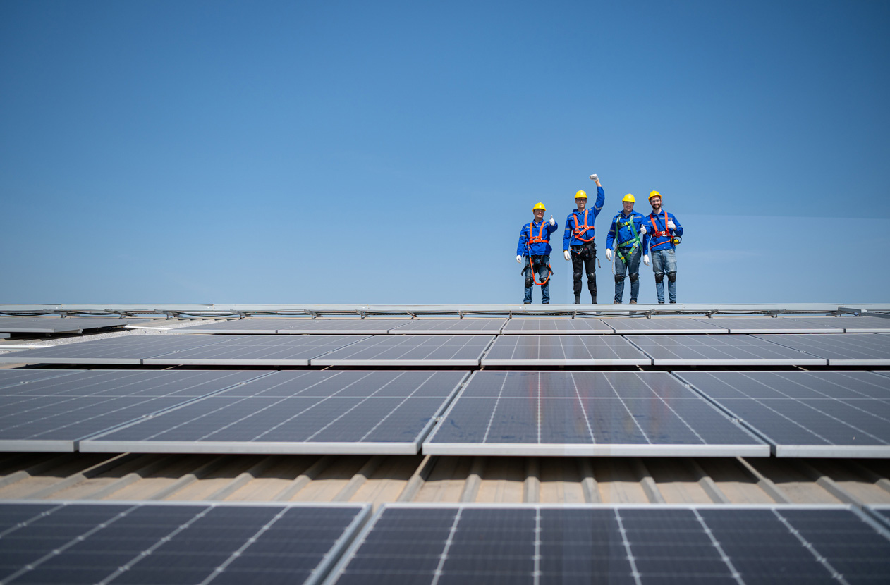 Group of engineers standing on solar panels with blue sky in the background
